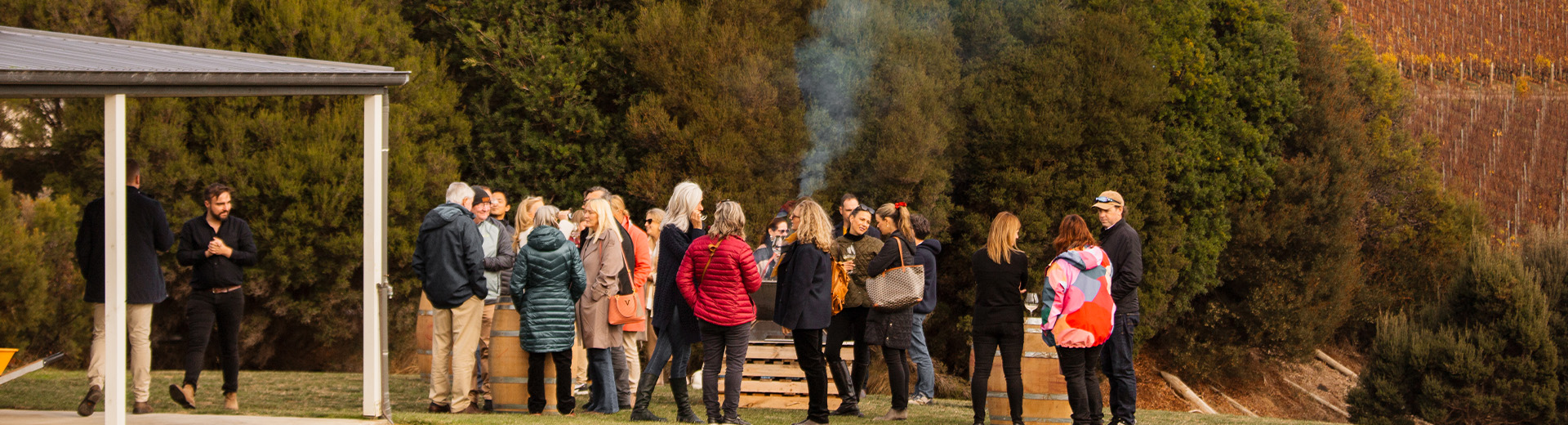 A group of people gathered outdoors at a wine event in a scenic vineyard setting